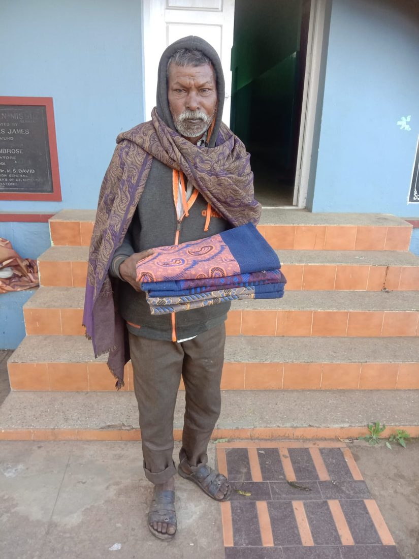 Blankets handed to a man sleeping rough, outside the mission.